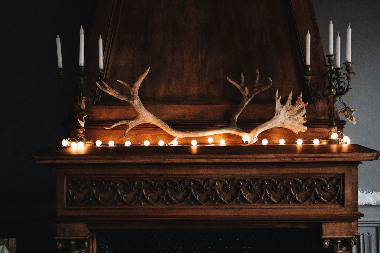 A beautifully decorated wooden mantel featuring antlers and candles creating a cozy interior decor ambiance.